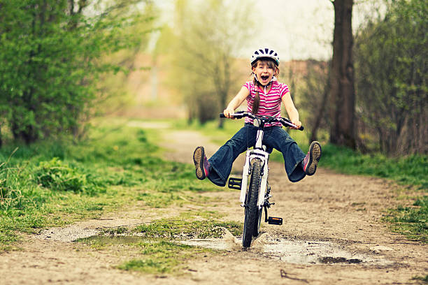 Little girl riding a bike through a puddle